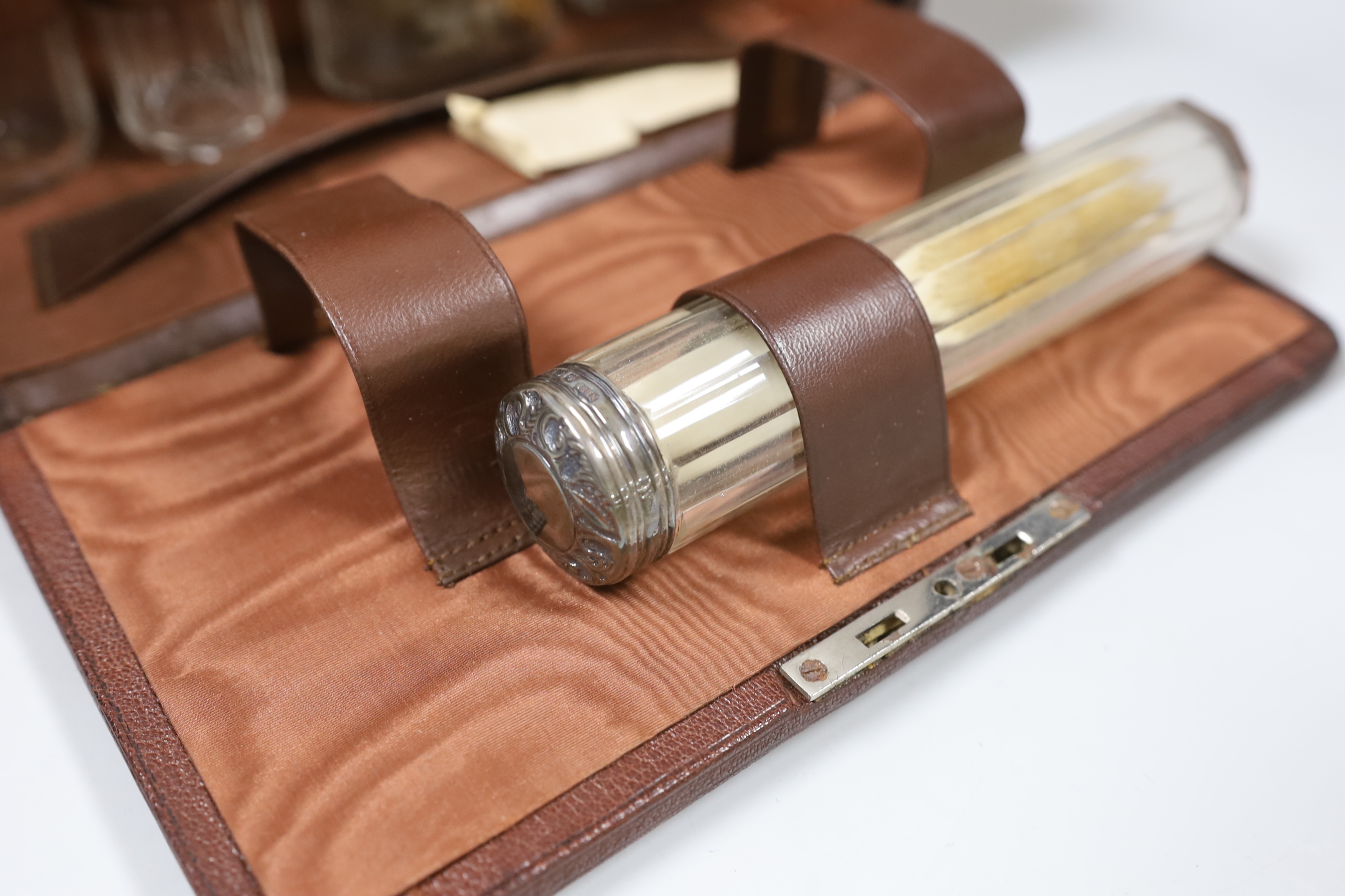 A George V leather travelling toilet case, containing five silver mounted glass jars, Birmingham, 1910, (incomplete), case 25cm.